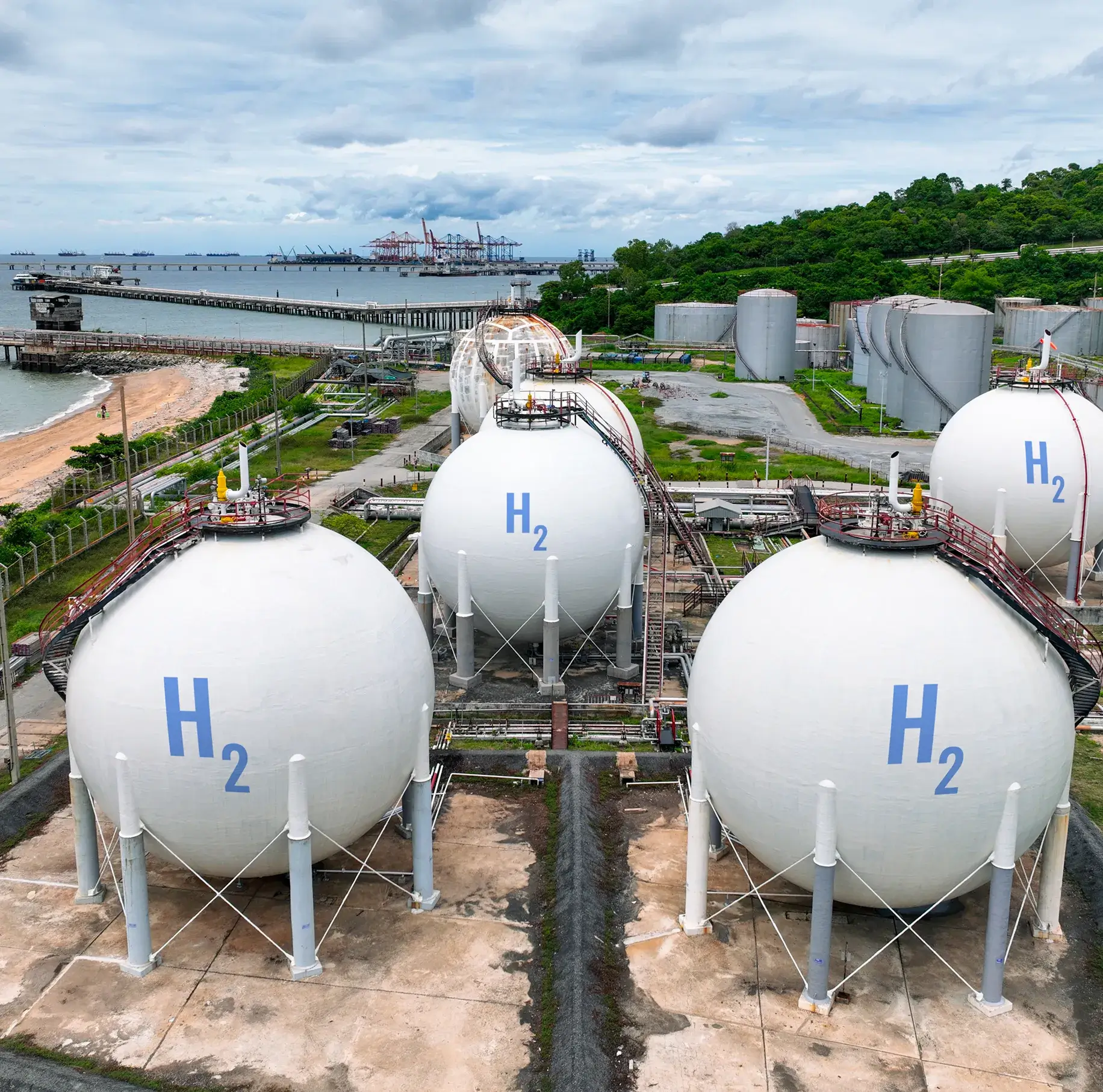 Hydrogen storage tanks near waterfront industrial area.