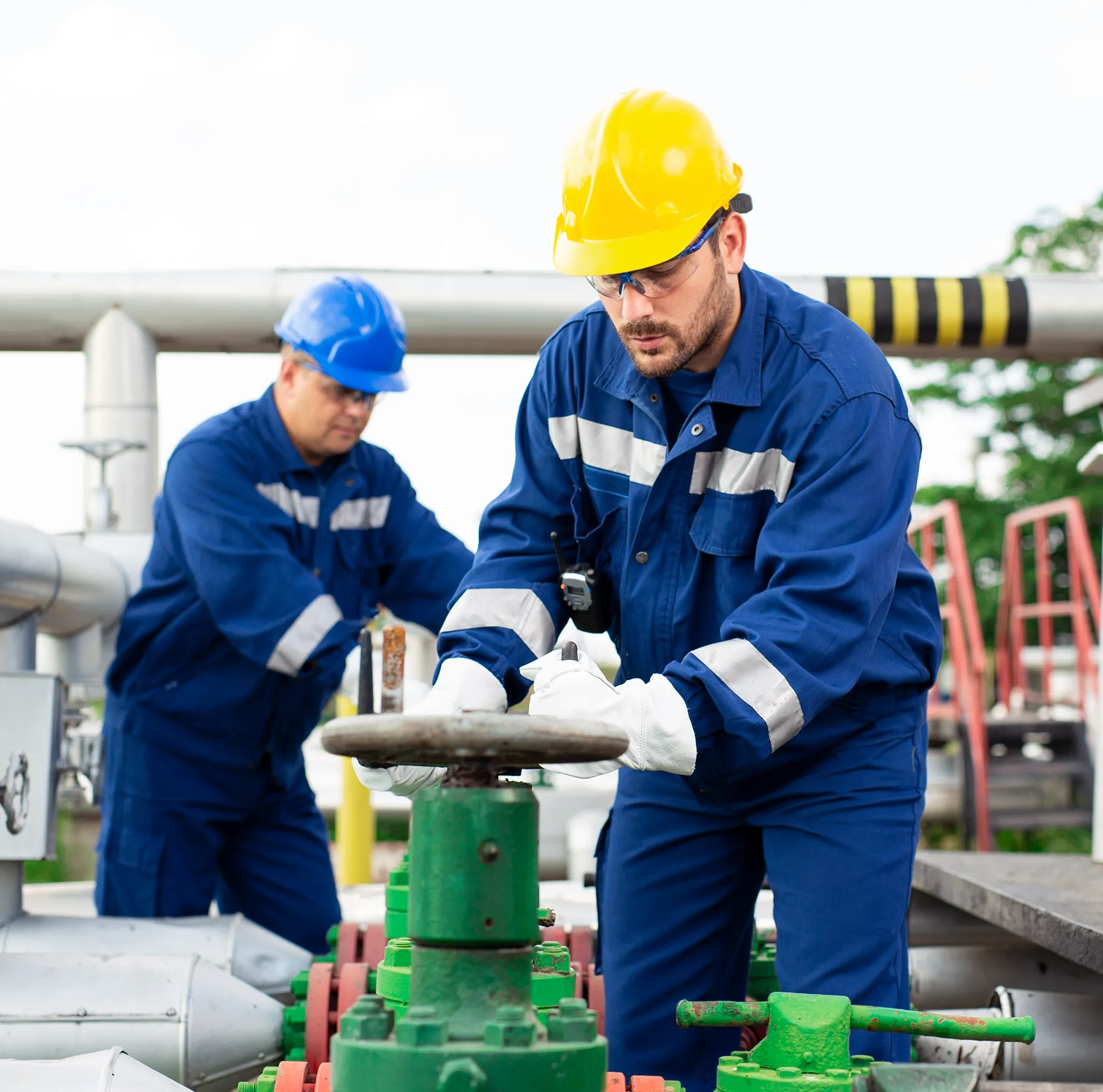 Two workers operating industrial equipment outdoors.